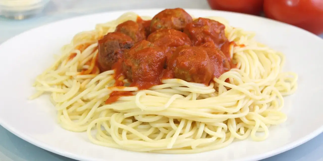 Un plato de espaguetis con albóndigas cubiertos de salsa roja.