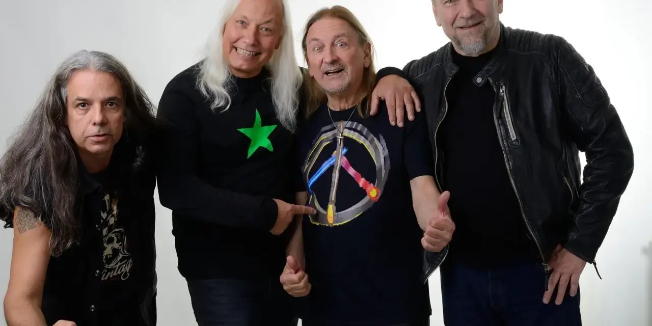 Czterech mężczyzn, TSA Dream Team, pozuje do zdjęcia. Dwóch z nich ma długie włosy, jeden w czarnej koszulce z zieloną gwiazdą, drugi w koszulce z symbolem pokoju.