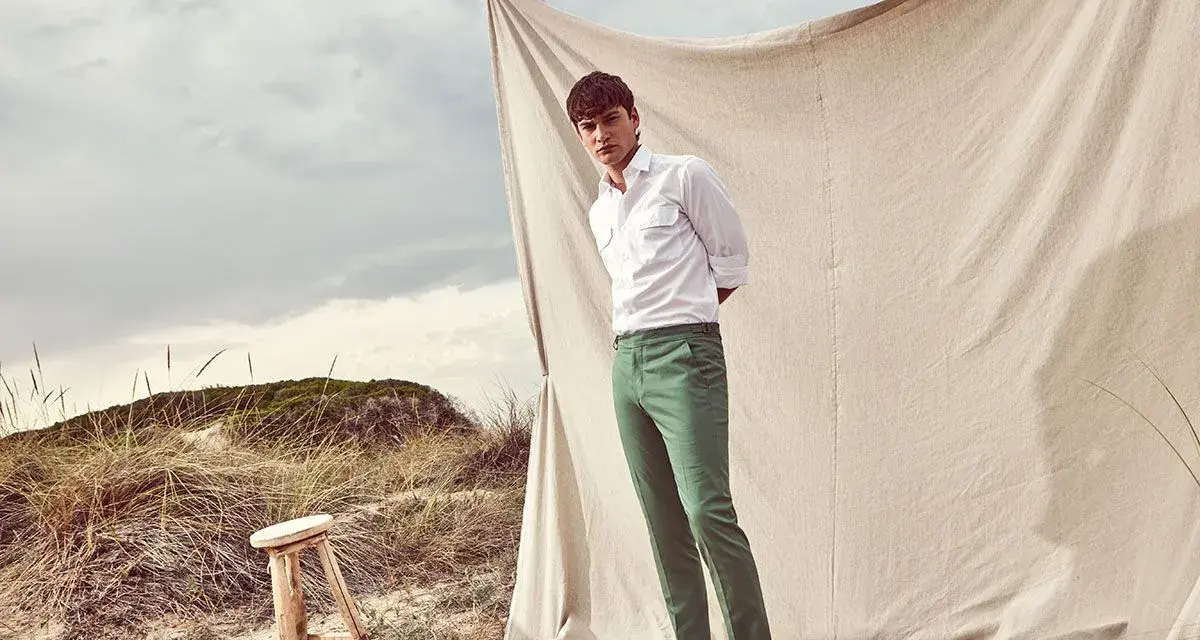 Un uomo con camicia bianca e pantalone verde, un look perfetto per l'estate. Scopri come abbinare un pantalone verde per un outfit fresco e alla moda.