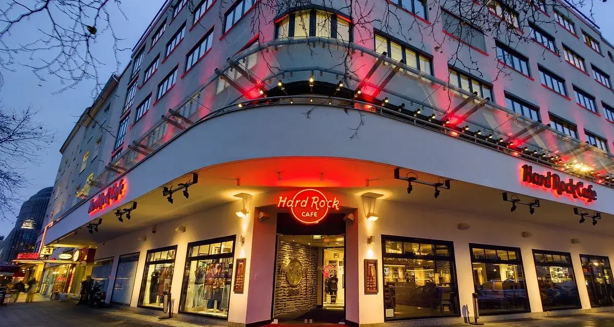 Das Hard Rock Cafe Berlin erstrahlt im Abendlicht. Rote Neonschilder und Beleuchtung werfen einen warmen Schein auf die Fassade des Gebäudes.