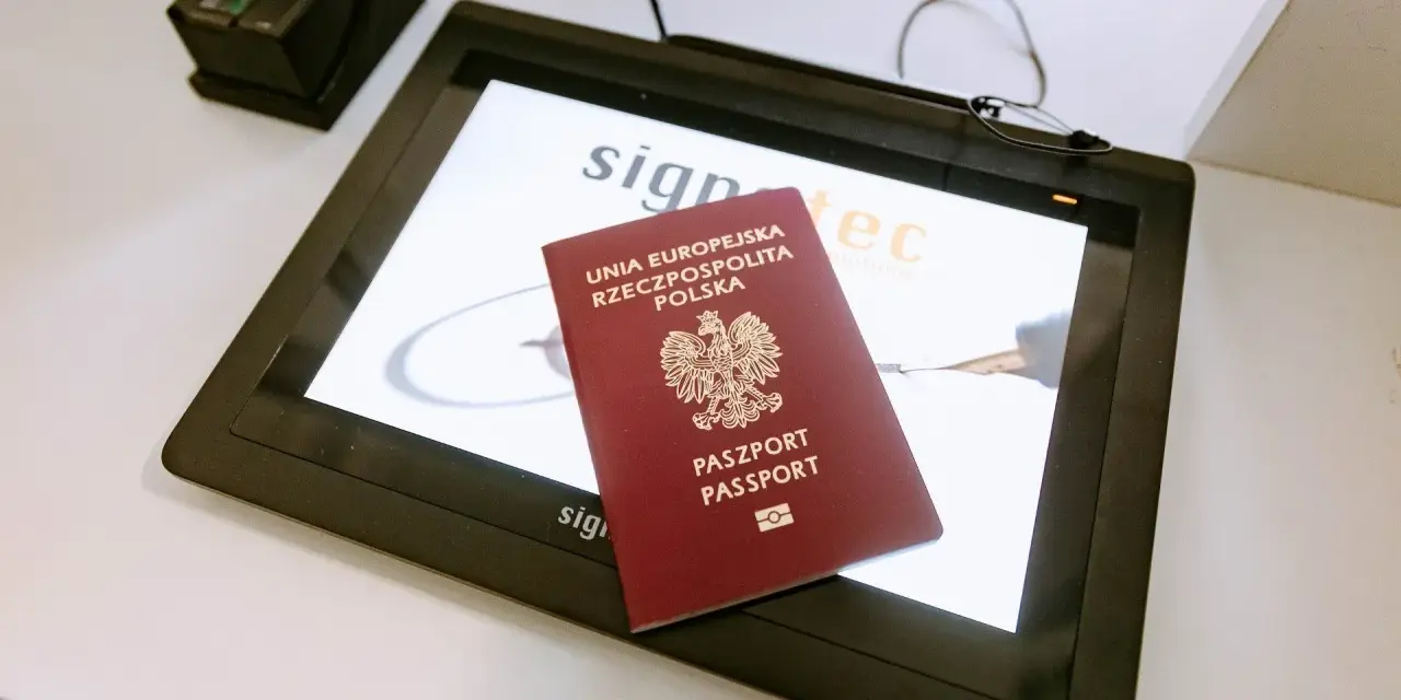 Polski paszport na ekranie tabletu w biurze paszportowym Włocławek. Obok skaner linii papilarnych.