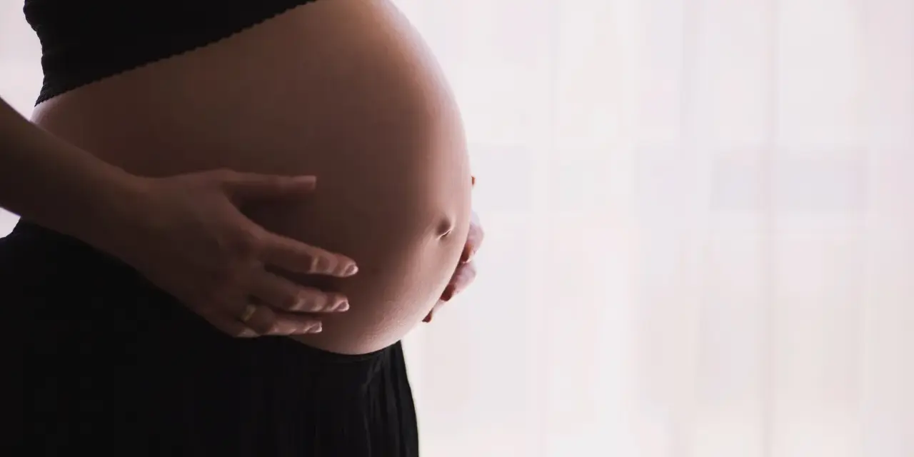 Gravid mage med händer som varsamt håller om den. Kanske funderar hon på proteinpulver gravid för att ge extra näring.