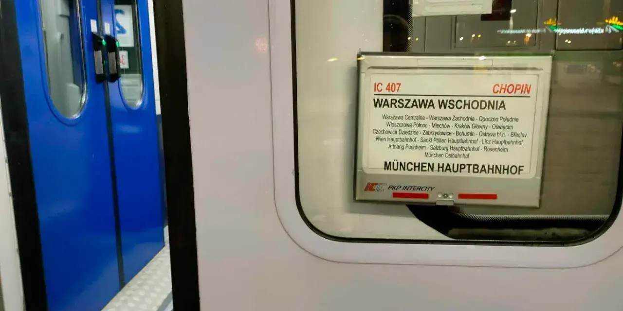 Tabliczka z rozkładem jazdy pociągu IC 407 Chopin na tle niebieskich drzwi pociągu.