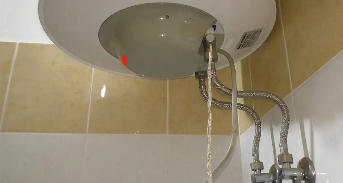 Dettaglio del fondo di uno scaldabagno con tubi flessibili e valvola di sicurezza. Guida su come regolare valvola di sicurezza scaldabagno.