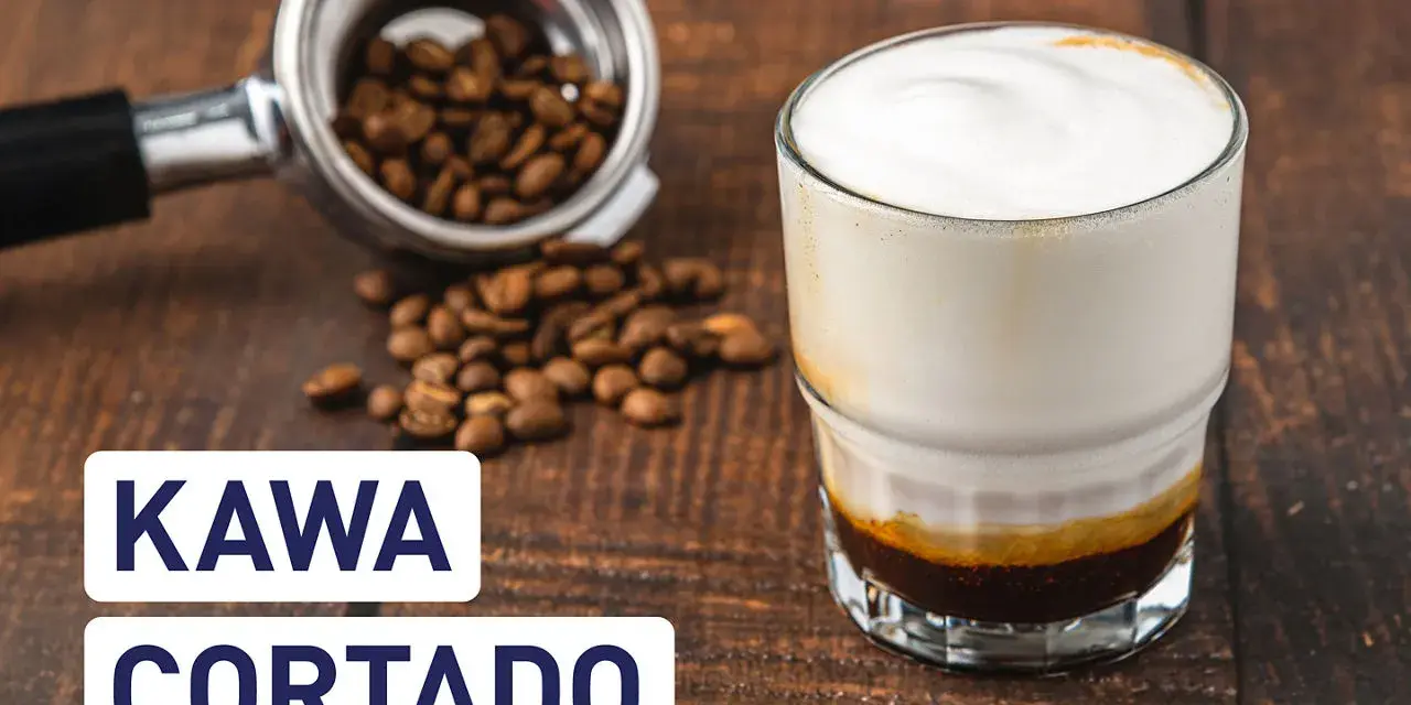 Kawa cortado z mleczną pianką, obok portafilter z ziarnami kawy. Idealny napój na poranek.