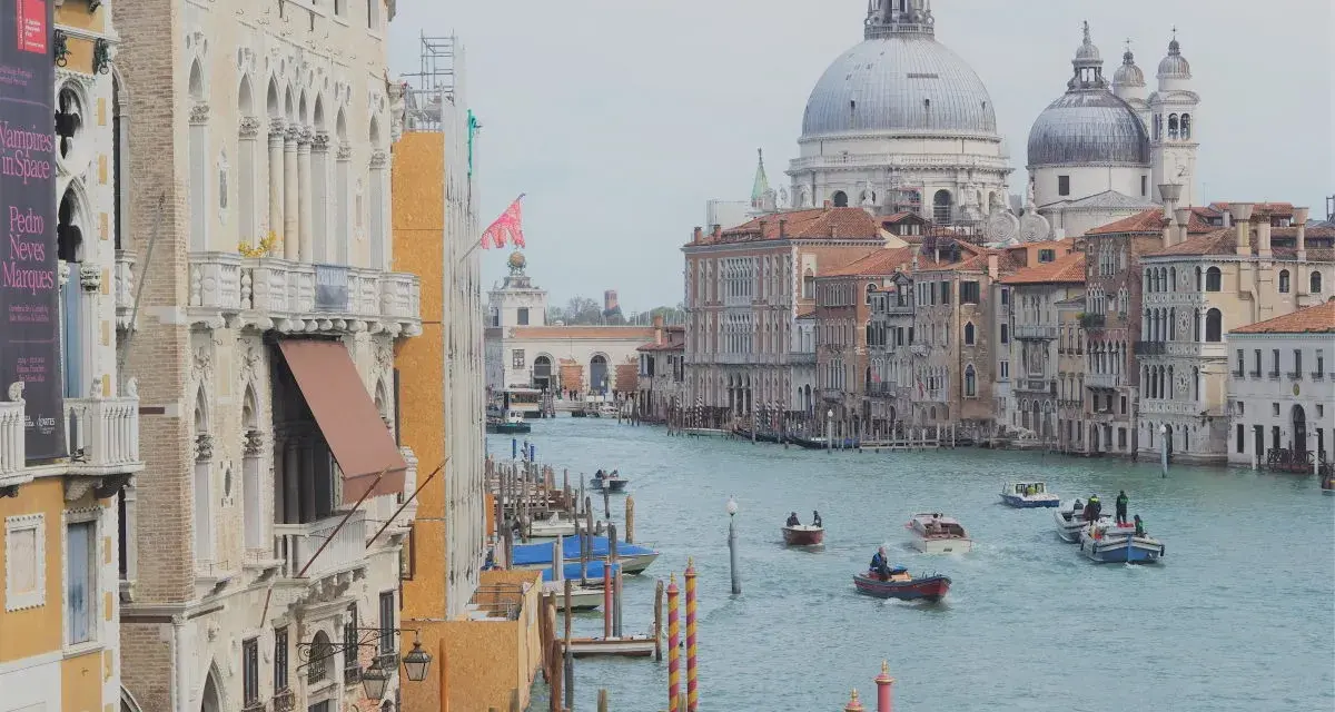 Canale di Venezia con barche, palazzi storici e la Basilica di Santa Maria della Salute. Il **costo entrata Venezia** è un tema attuale per i turisti.