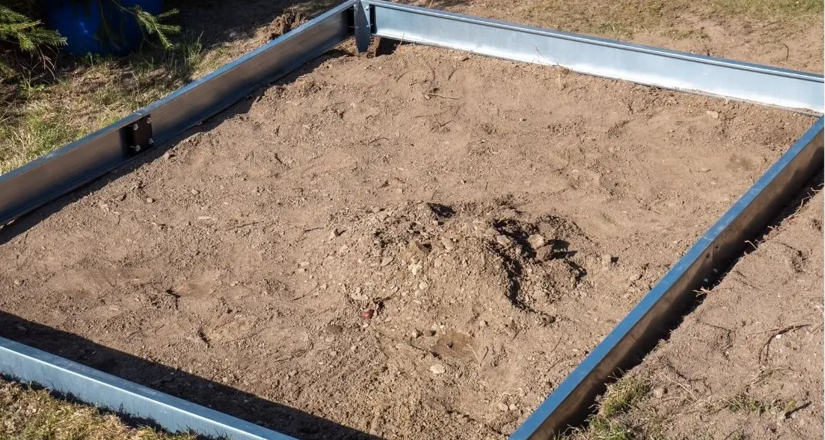 Metalowa rama na ziemi, gotowa na zrobienie fundamentu pod szklarnię.
