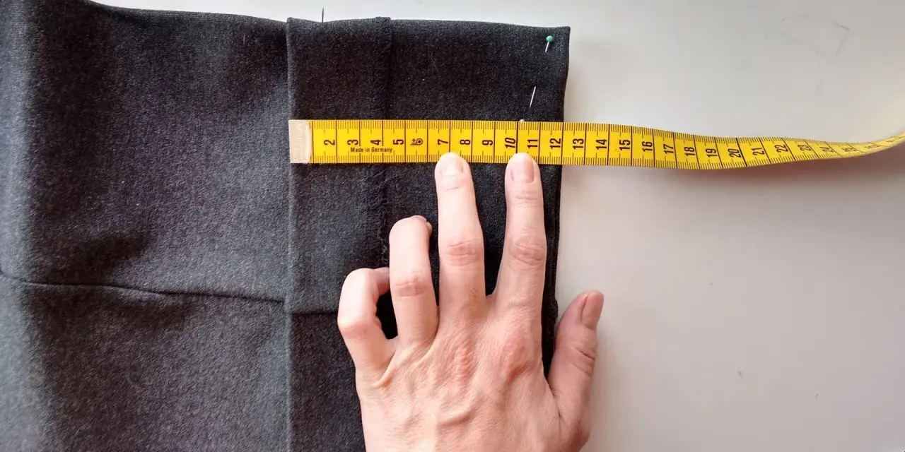 Mierzysz, jak skrócić spodnie ręcznie. Miarka krawiecka pokazuje ok. 11 cm.
