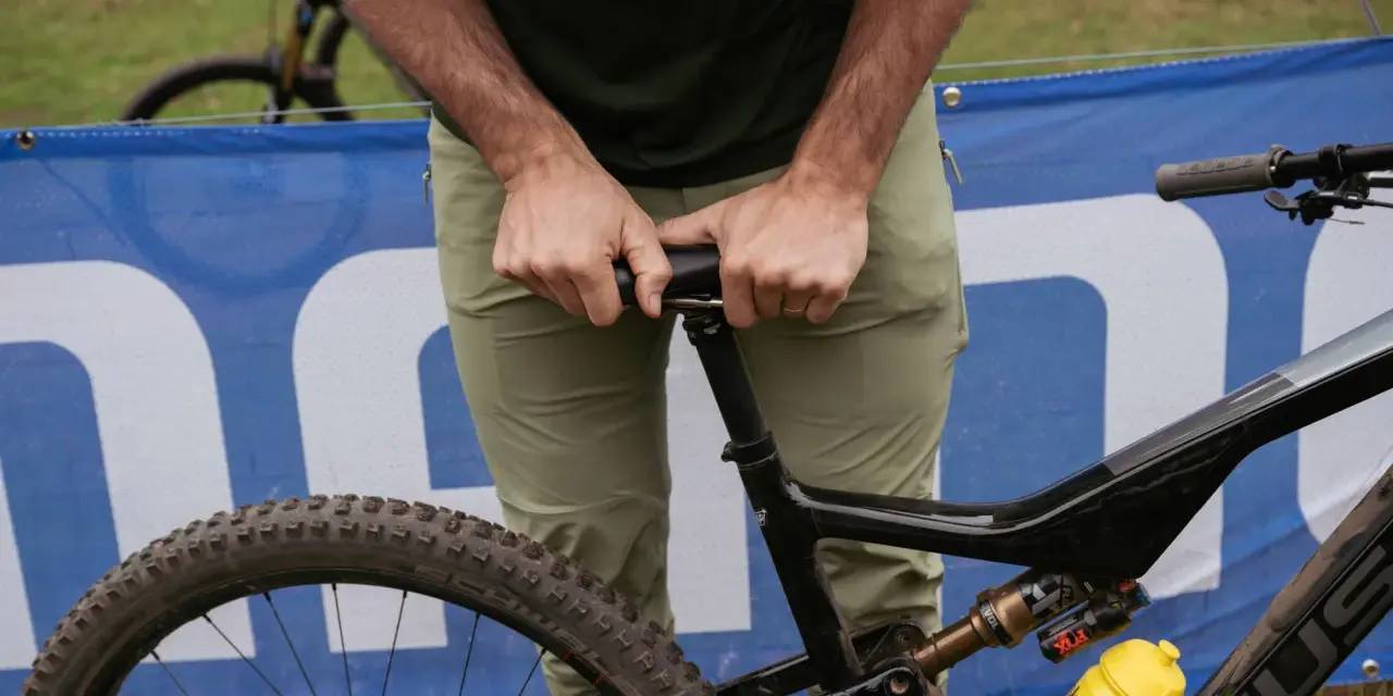 A rider adjusts their seat on a full-suspension bike, ready for an enduro mountain biking adventure.