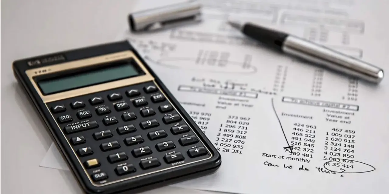 Calculadora y bolígrafo sobre un balance de situación. El balance de situación muestra cifras de inversión y valor al cierre del año.
