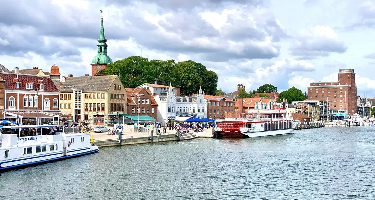 Hafen von Kappeln mit Schiffen und historischen Gebäuden. Entdecken Sie die Kappeln Geheimtipps für Ihren nächsten Urlaub.