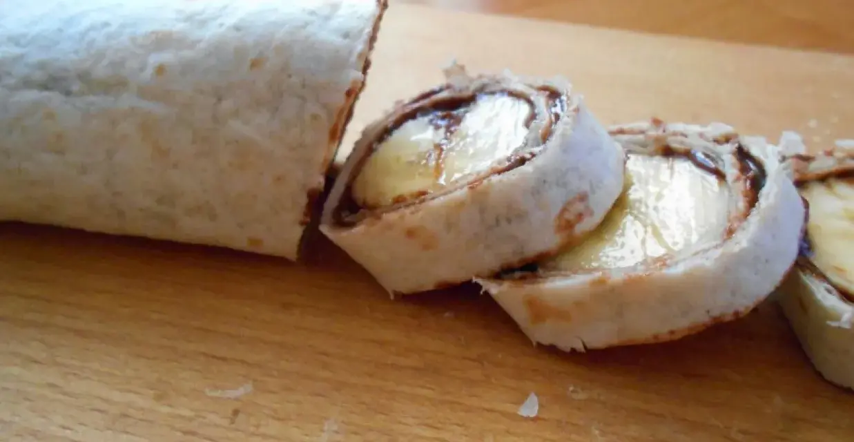 Słodka tortilla z bananem i czekoladą, pokrojona w rolki, wygląda jak pyszny deser.