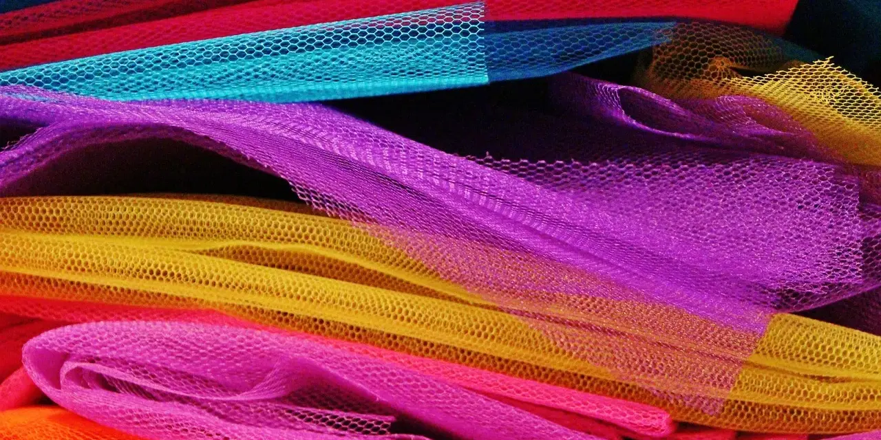 Un tas de **tulle** aux couleurs vives : orange, rose, jaune, violet, bleu et rouge.