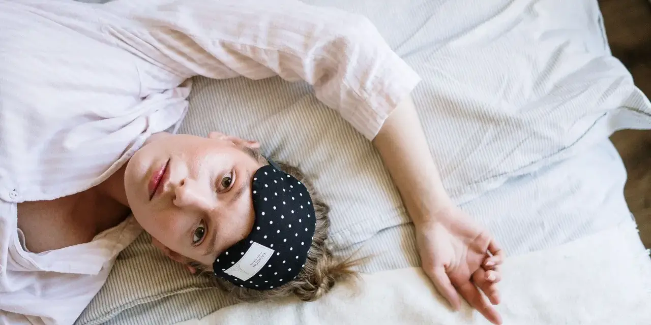 Donna con mascherina per dormire, cerca rimedi per l'insonnia da stress.