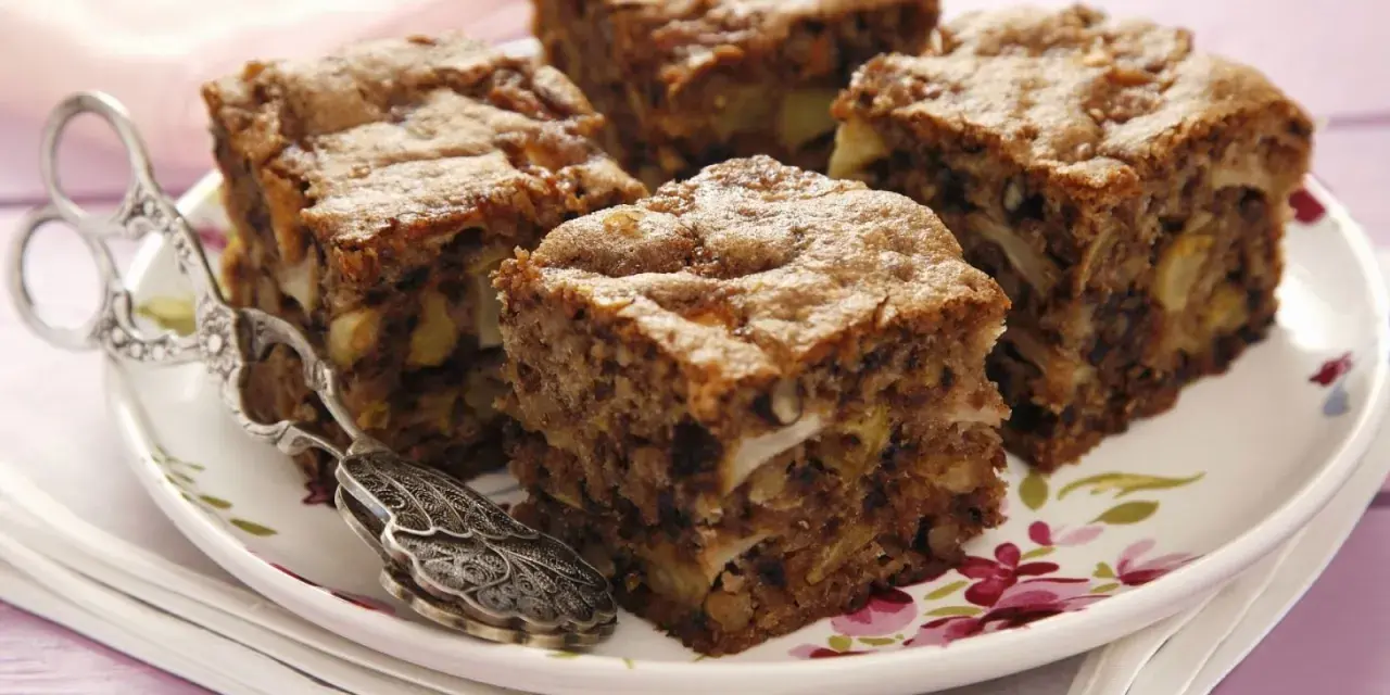 Vier Stücke saftiger Apfel Walnuss Kuchen auf einem Teller mit Blumenmuster, daneben ein antiker Tortenheber.