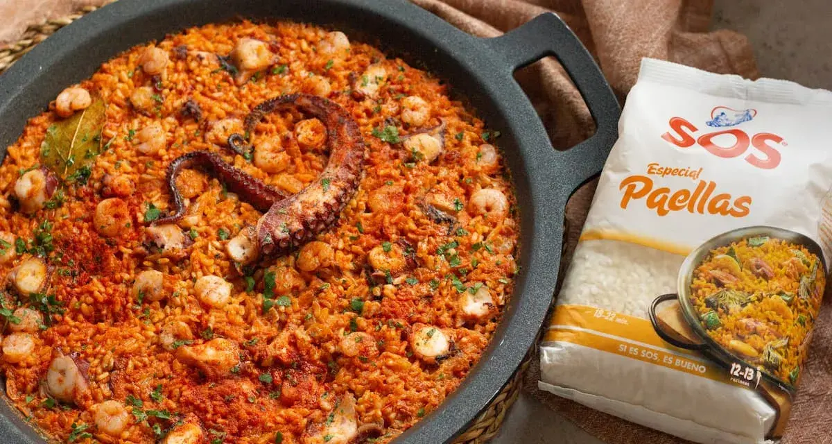 Paella de marisco con un tentáculo de pulpo visible, gambas y trozos de calamar. Al lado, un paquete de arroz SOS Especial Paellas.