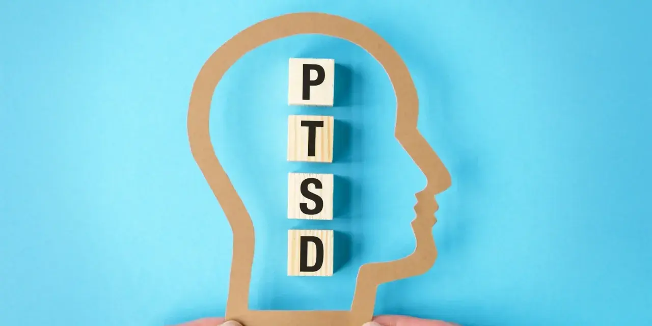 W głowie z papieru litery P, T, S, D układają się w słowo PTSD, symbolizując jego objawy.