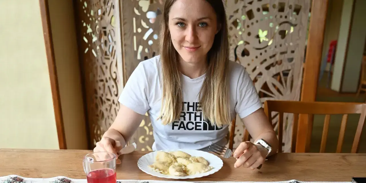 Kobieta przy stole z pierogami i surówką. Posiłek to świetny sposób, jak szybko uzupełnić białko w organizmie.