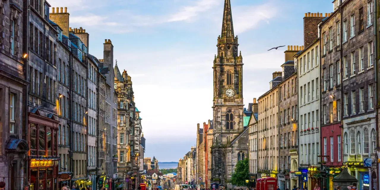 Edinburgh's Royal Mile with a clock tower and people walking on a cobblestone street.