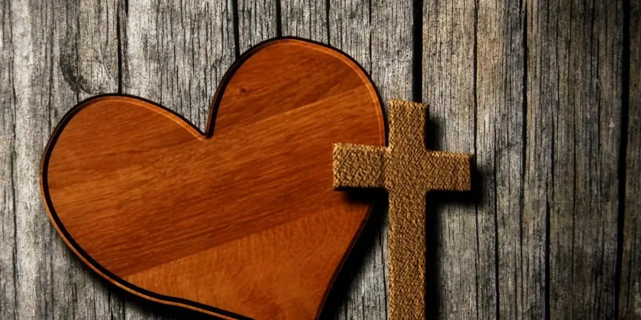 Holzherz und Kreuz auf grober Holzoberfläche. Ein Symbol für Liebe und Glauben, wie in Lukas 23,34.