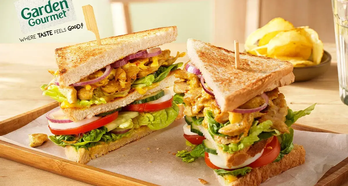 Zwei üppige Garden Gourmet Club Sandwiches mit knackigem Salat, Tomaten, Gurken und Zwiebeln auf getoastetem Brot.