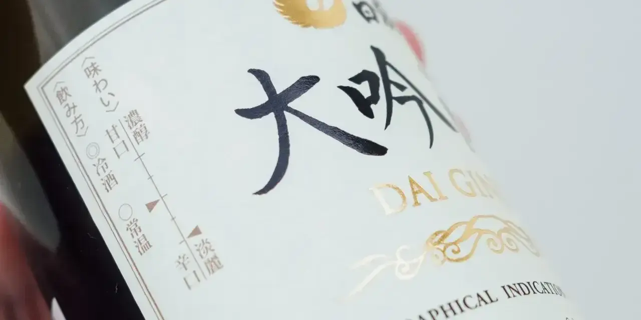 Butelka sake z napisem "DAI GIN". Na etykiecie widać skalę smaku i temperatury podania.