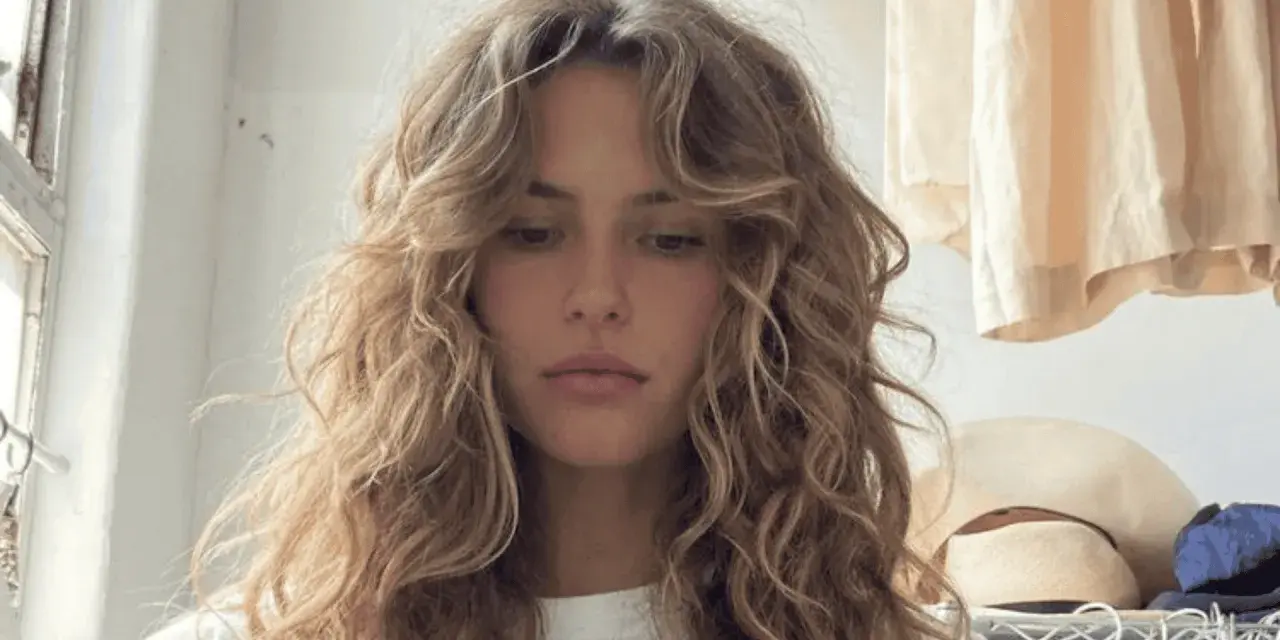 Chica con pelo rizado y flequillo desfilado, inspirador para tipos de flequillo para pelo rizado.