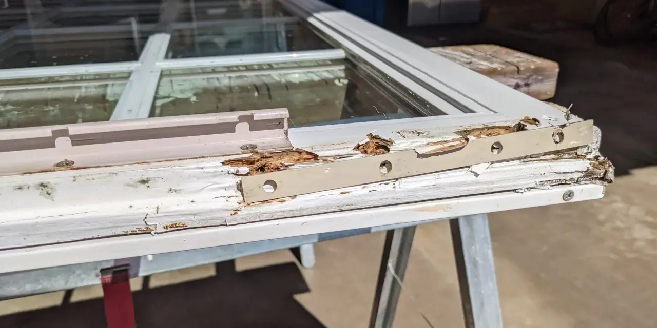 Damaged wood window frame, showing rot and peeling paint, indicating a need for wood window repair.