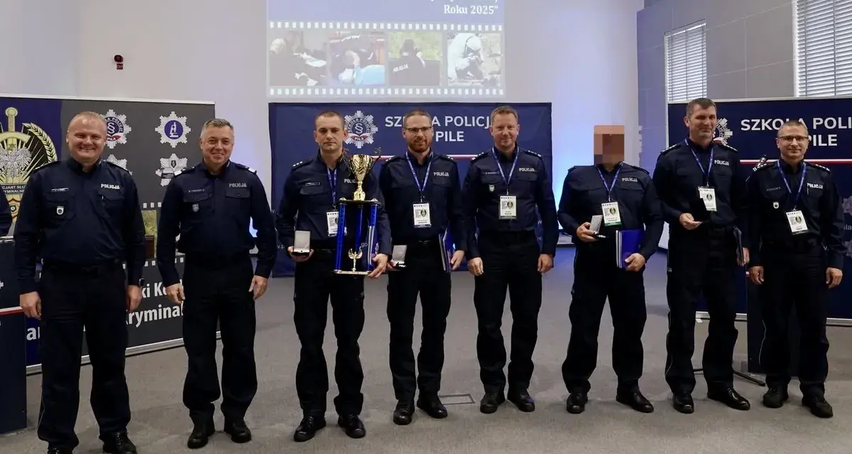 Policjanci w mundurach stoją w rzędzie, niektórzy trzymają nagrody i dyplomy.