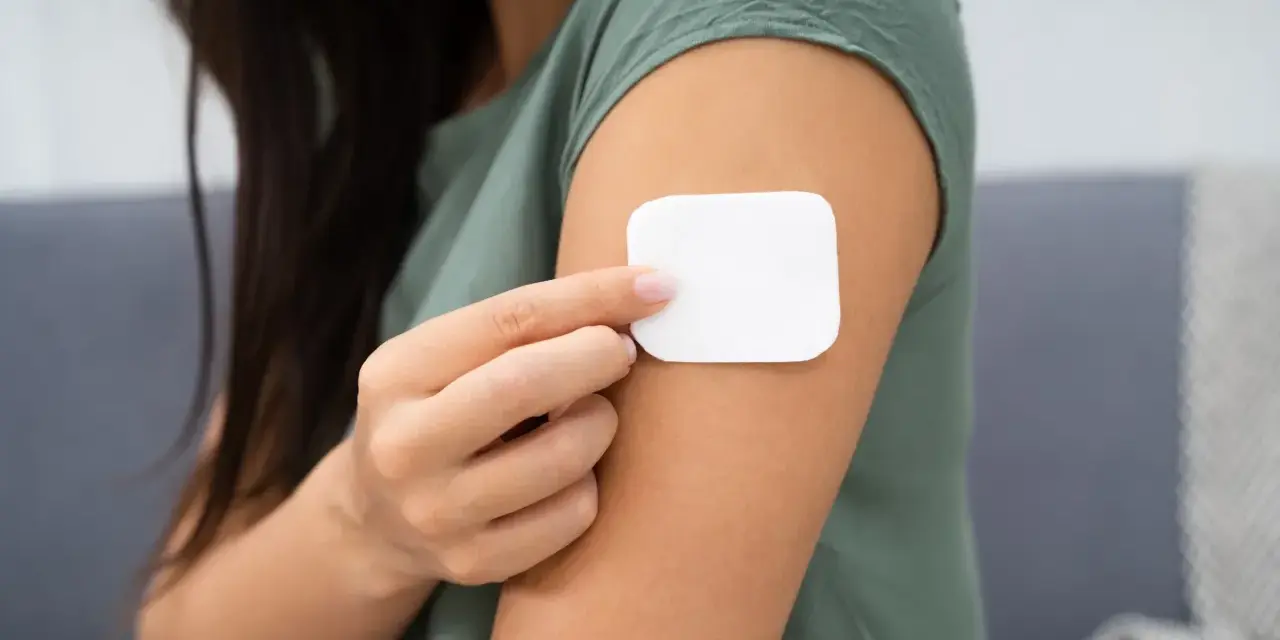 Kobieta przykleja plaster antykoncepcyjny. Przed użyciem warto zapoznać się z przeciwwskazaniami.