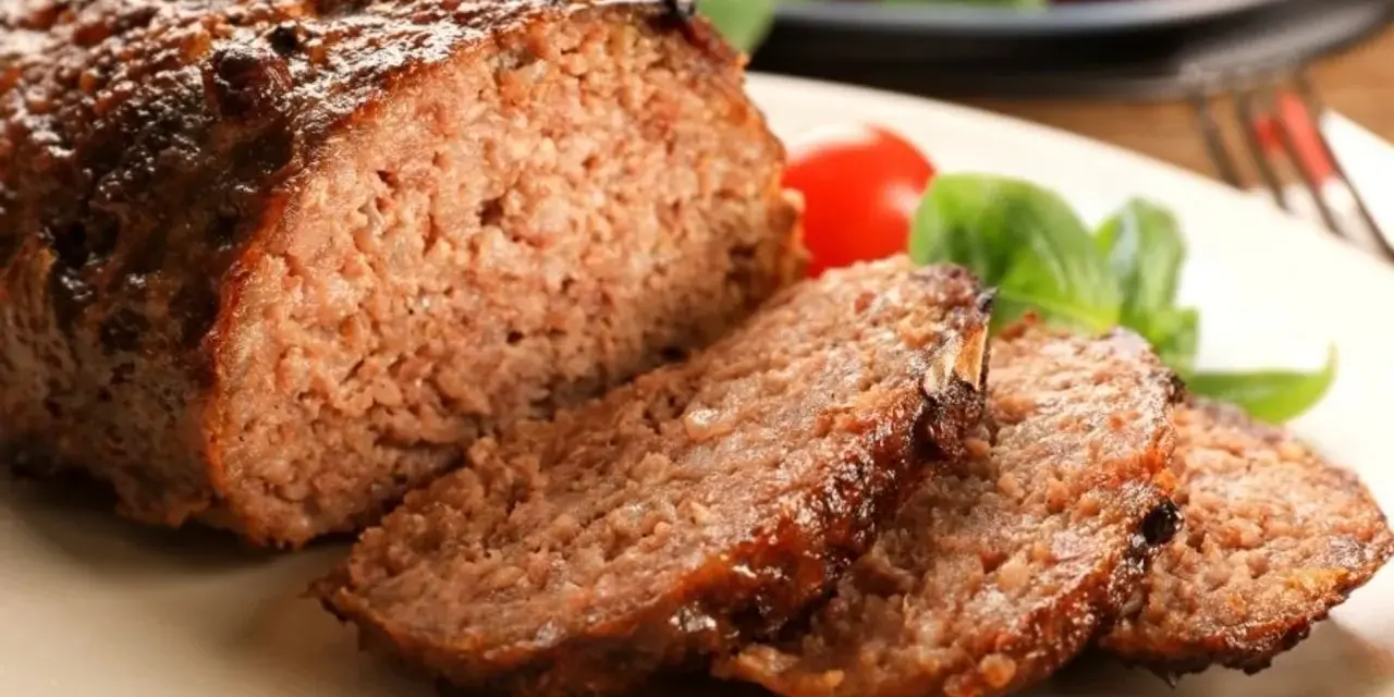 Soczysta, rumiana pieczeń rzymska, pokrojona w plastry, z pomidorkami i bazylią. To najlepsza pieczeń rzymska, jaką można sobie wymarzyć!