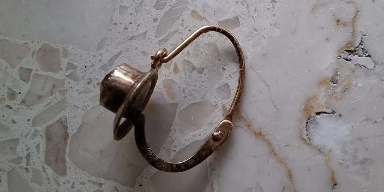 Orecchino d'oro con pietra scura, un po' consumato dal tempo, segno che l'oro si ossida.