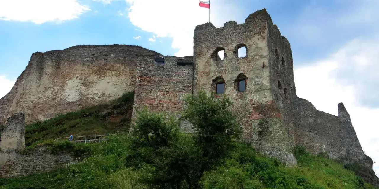 Zamek Czorsztyn, majestatyczne ruiny na wzgórzu, dumnie prezentuje polską flagę na tle błękitnego nieba.