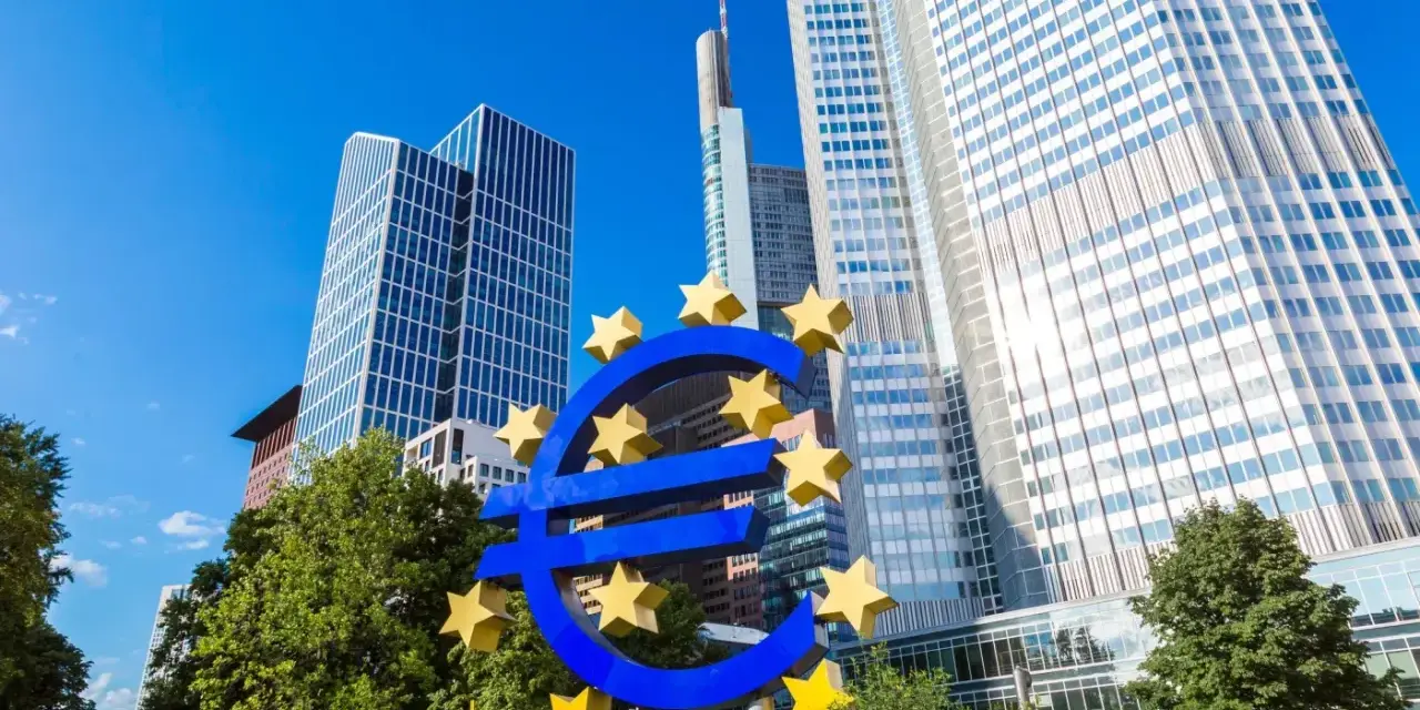 Symbol euro przed nowoczesnymi wieżowcami, siedziba europejskiego banku centralnego.