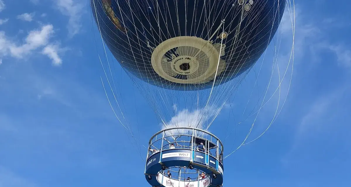 Weltballon über Berlin bei schönem Wetter. Die Gondel mit Passagieren schwebt unter dem riesigen Globus-Ballon.