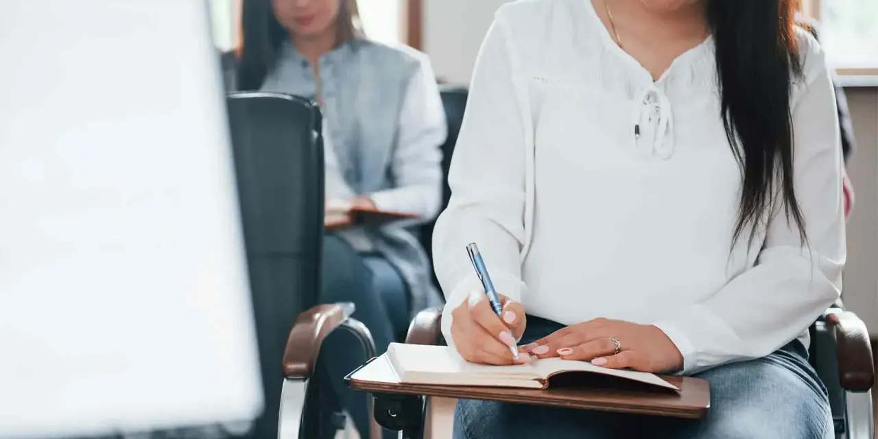 Estudiantes toman notas en clase. Se registran los gastos de formación en la cuenta contable.