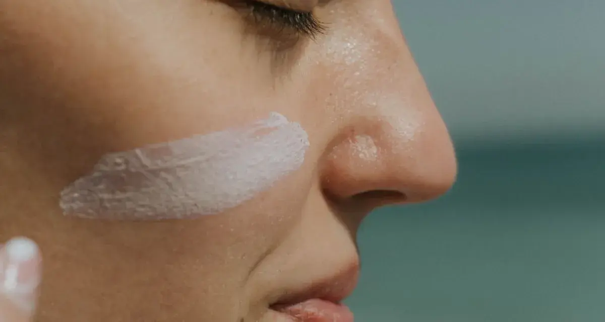 Rostro de mujer con una pincelada de crema solar biodegradable en la mejilla.