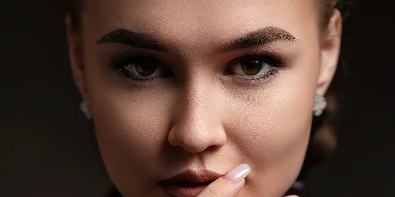 Un gros plan sur le visage d'une femme, ses sourcils parfaitement dessinés après une séance d'épilation.