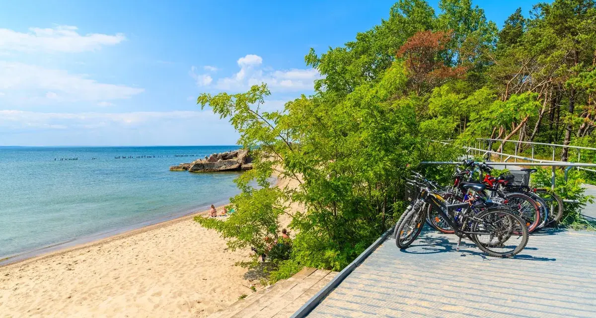 Rowerzyści odpoczywają na plaży, a ich rowery czekają na dalszą podróż po malowniczych pomorskich trasach rowerowych.