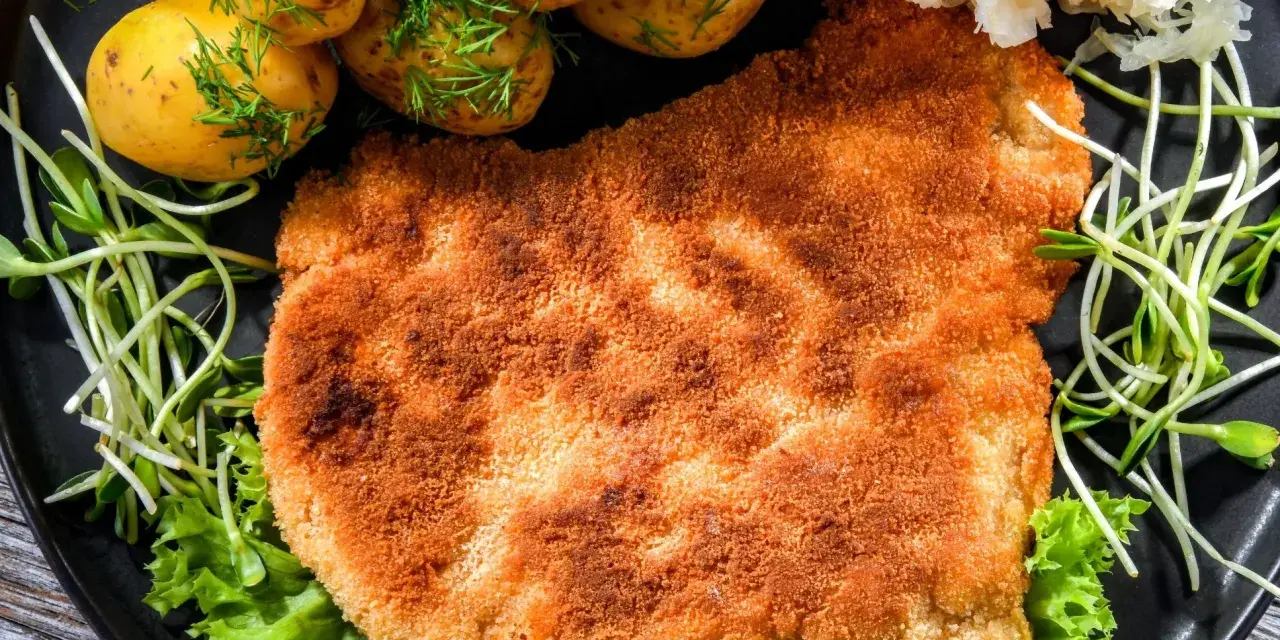 Chrupiący schabowy w panko, podany z młodymi ziemniaczkami, surówką i świeżą sałatą. Prawdziwa uczta dla podniebienia!