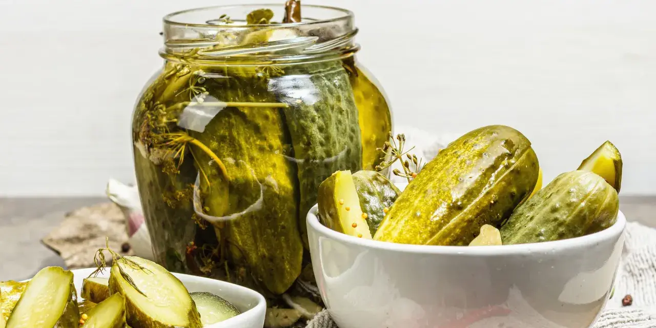 Vaso di cetriolini in agrodolce, con alcuni in una ciotola. Perfetti per un antipasto croccante e saporito.