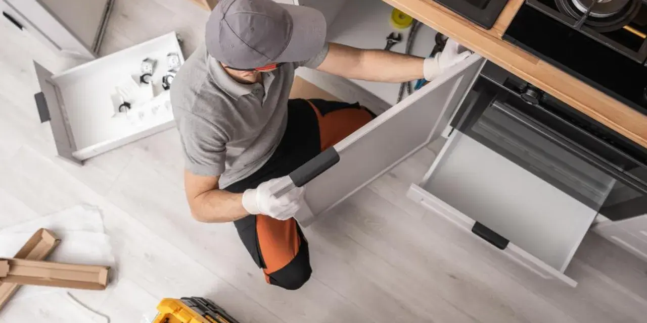 Instalador trabajando en la reforma de cocina, montando cajones y armarios.