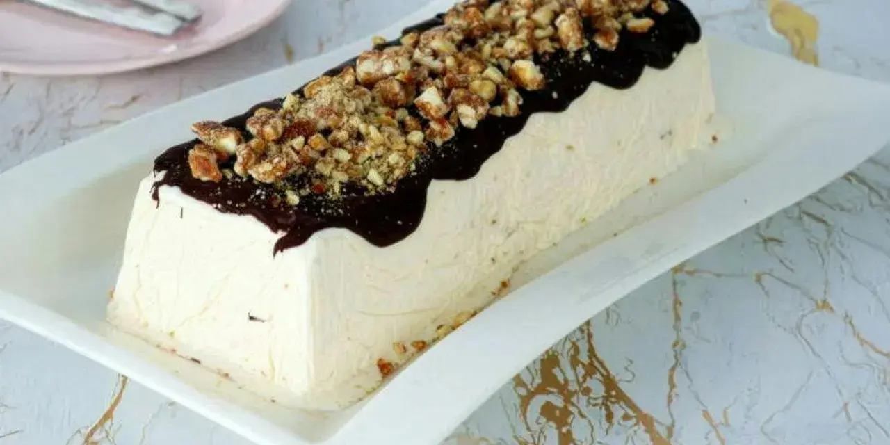 Un delizioso parfait di mandorle, ricoperto di cioccolato fuso e granella croccante, pronto per essere gustato.
