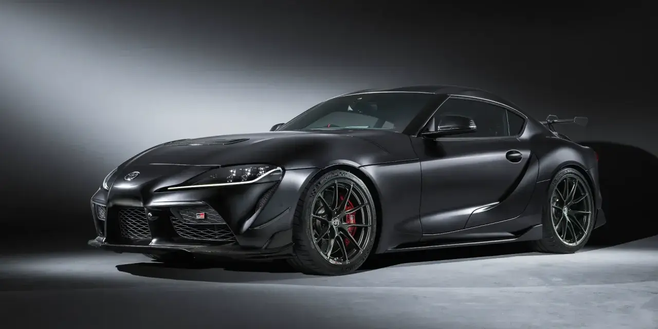 Matowa czerń podkreśla agresywną sylwetkę sportowego coupe Toyota GR Supra. Widoczne czerwone zaciski hamulcowe i aerodynamiczne dodatki.