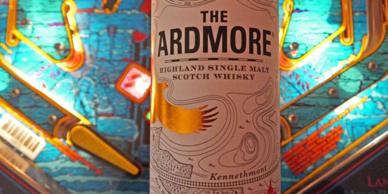 Flasche "The Ardmore" Highland Single Malt Scotch Whisky steht vor einem bunten Flipperautomaten. Ein spannender Ardmore Whisky Test!