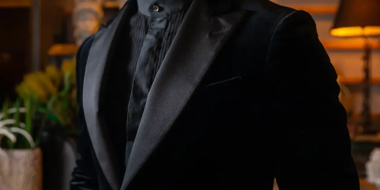Uomo con abito nero in velluto, camicia con jabot e cravatta. Eleganza senza tempo per un abbinamento perfetto.