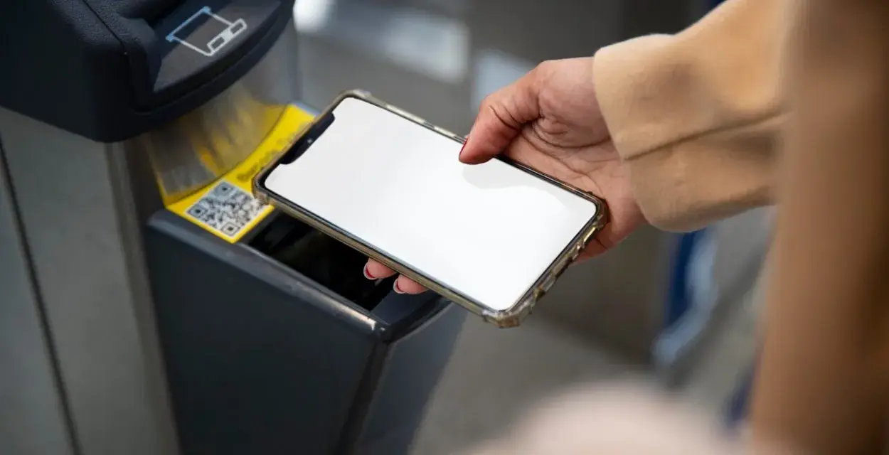 Dłoń zbliża smartfon do czytnika biletów. Szybkie płatności przez Euronet, bez prowizji PKO.