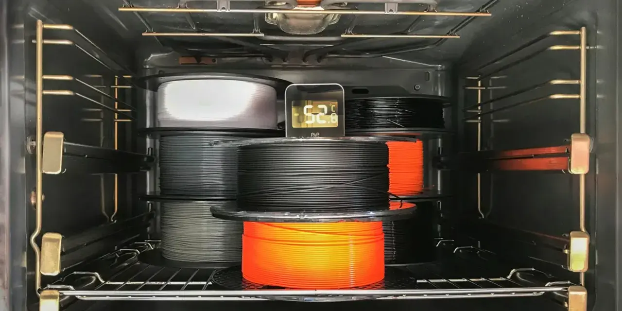 Szpule filamentu do druku 3D, materiał higroskopijny, suszone w piekarniku. Termometr pokazuje 52.8°C.