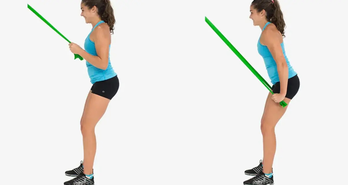 Kvinnlig atlet utför triceps pushdown med ett grönt träningsband.