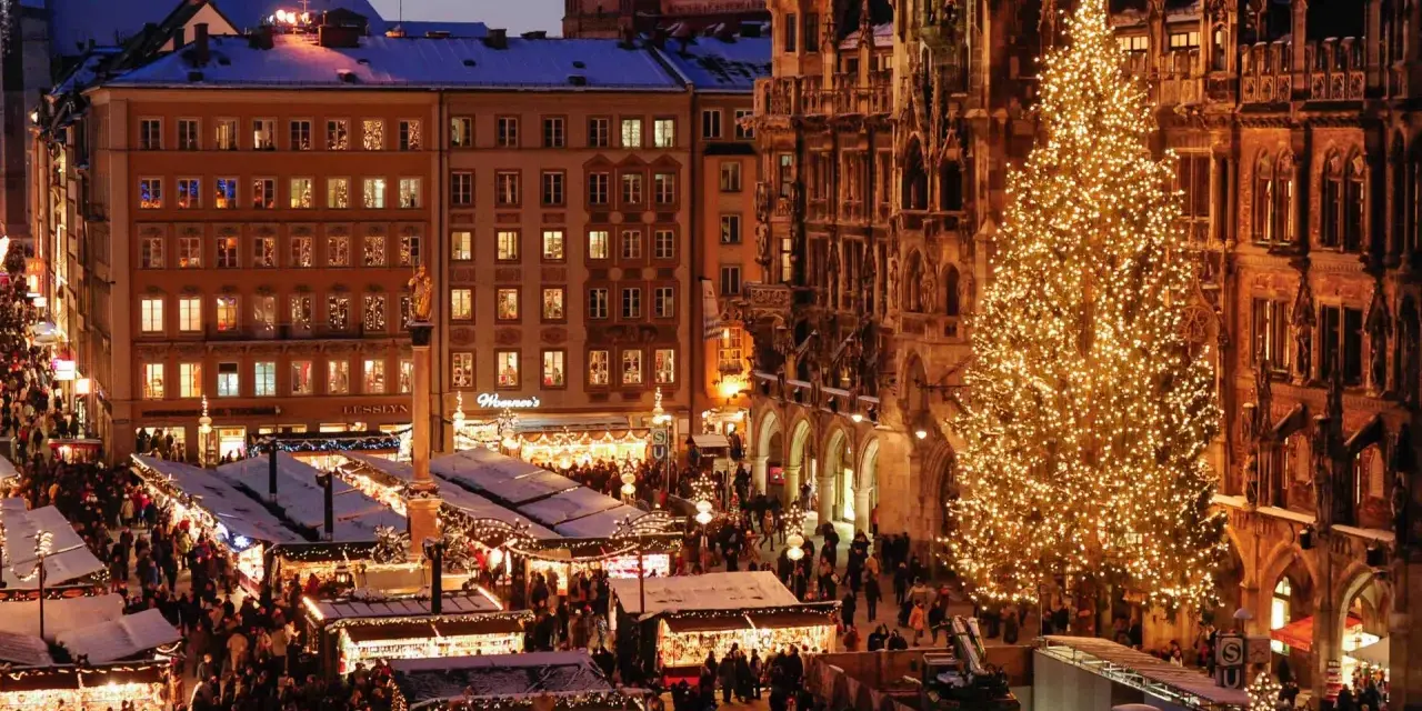 A bustling Christmas market in Munich, Germany, with a towering, illuminated tree and snow-dusted stalls.